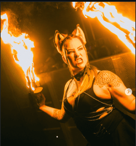 SIN FIRE performer holding flaming torches in a dark venue